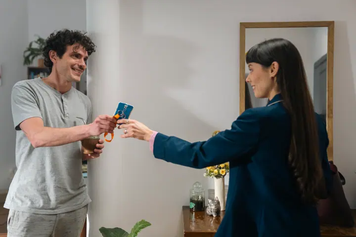 Un hombre recibe sonriente su credencial en la puerta de su casa
